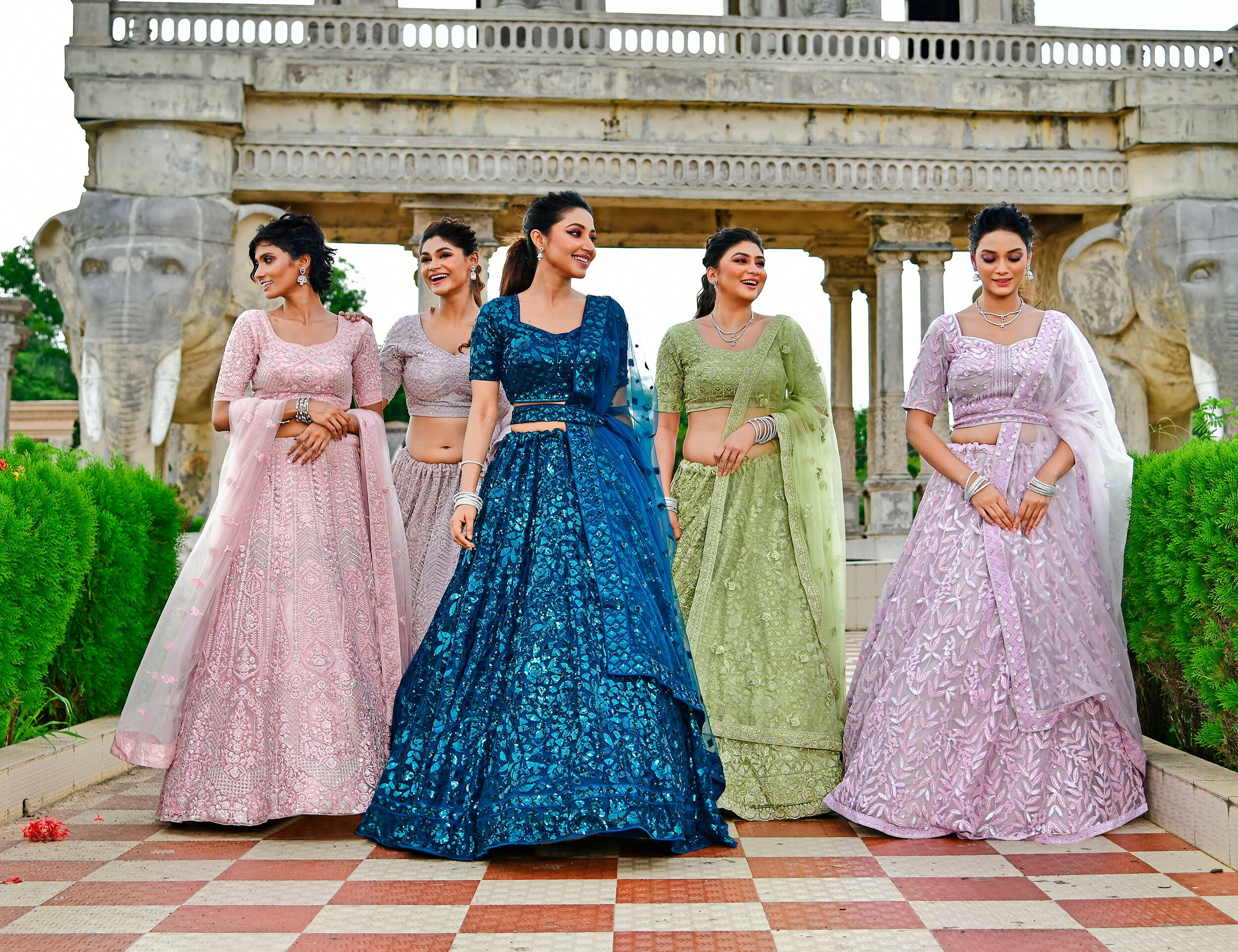 Stunning bride posing with her friends, all dressed in vibrant and elegant lehengas